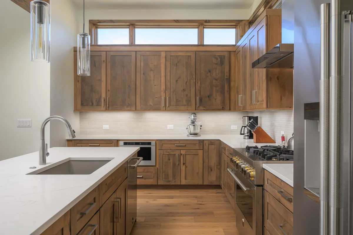 A well-lit kitchen with wood cabinetry, stainless steel appliances, and expansive countertops, bathed in natural light from large windows. The space feels both welcoming and highly functional, ideal for meal preparation, baking, and hosting gatherings.