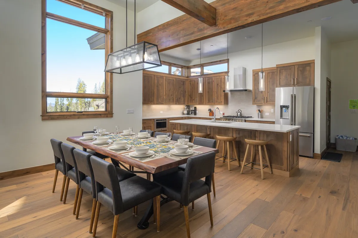 A spacious kitchen and dining area where a large dining table sits just steps from the kitchen island, with large windows providing bright, inviting light. The setup is perfect for both meal preparation and serving, fostering a communal atmosphere.